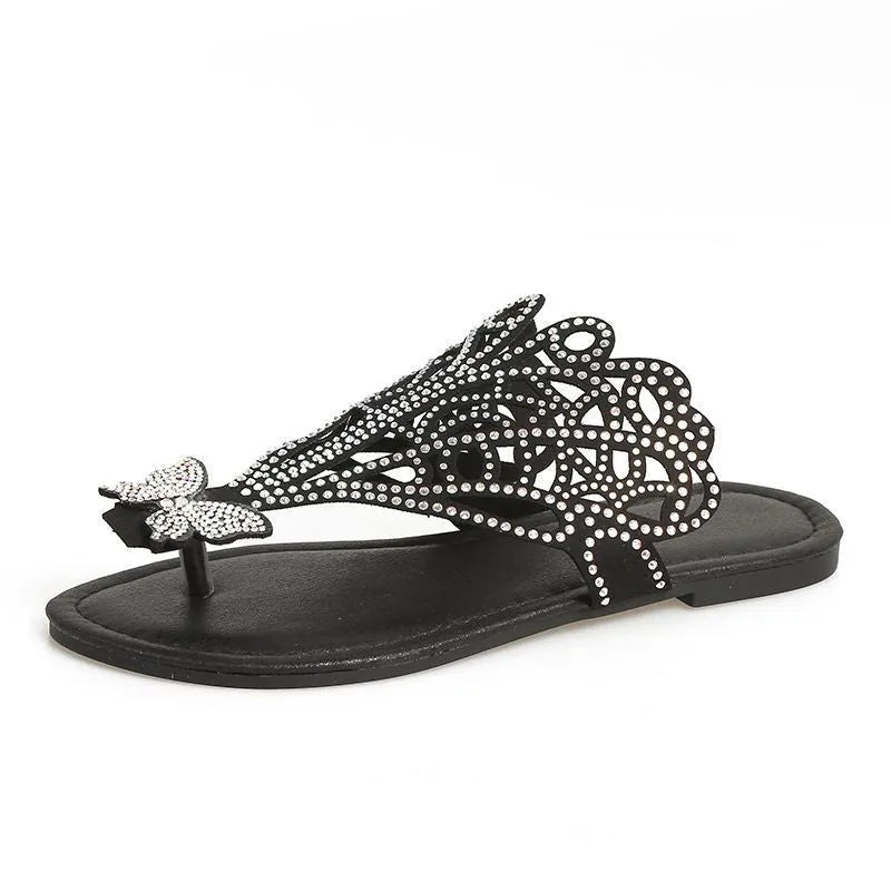 Women's black slip-on sandals with rhinestone decoration on the flip-toe and a flat rubber sole.