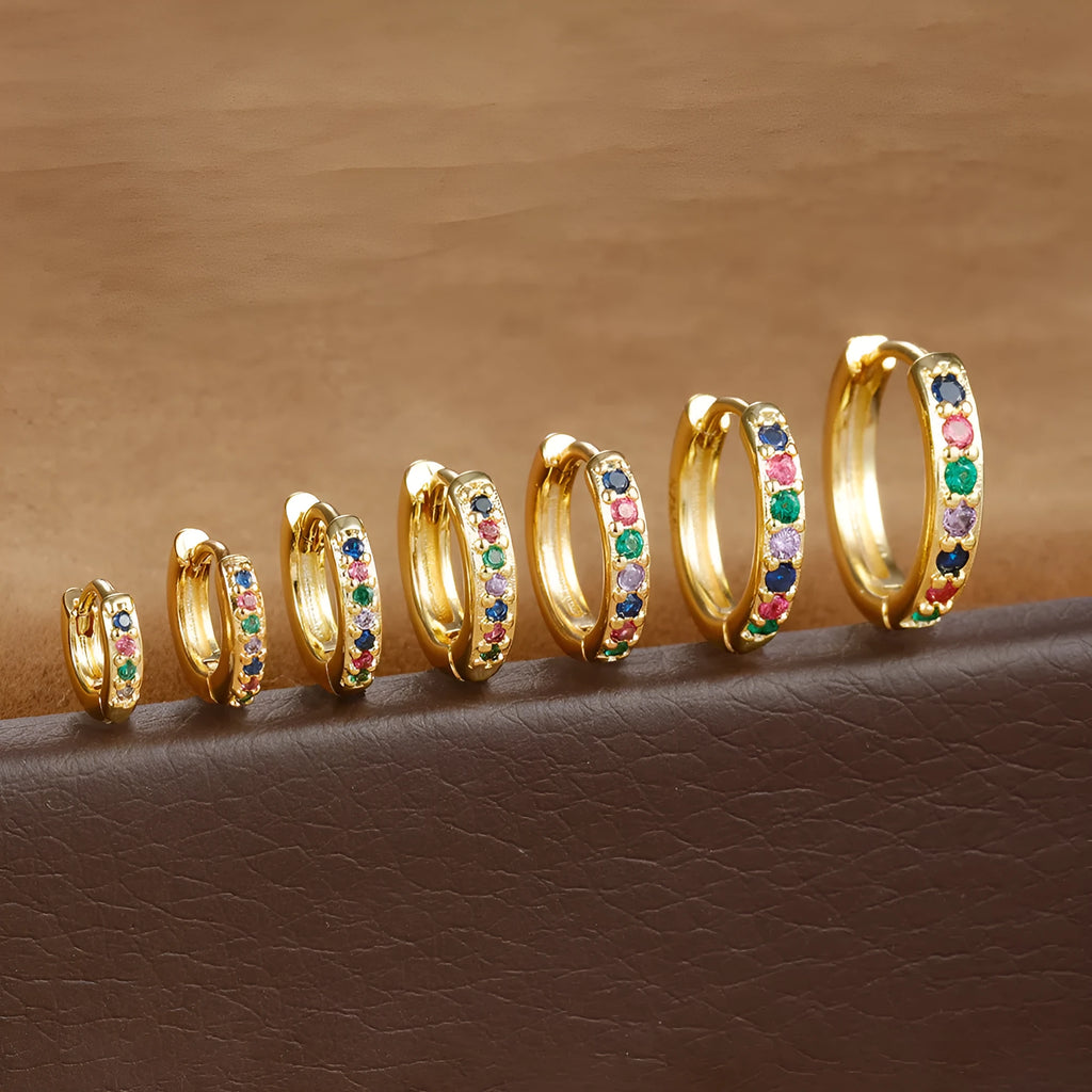 Gold, rose gold, and silver coloured geometric circle stud earrings with a perforated centre on a white background.
