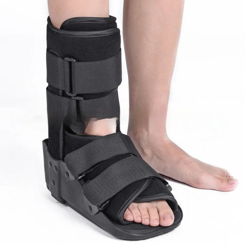 Grey Achilles tendon rehabilitation boot with aluminium side struts and a rubber sole, shown on a foot.