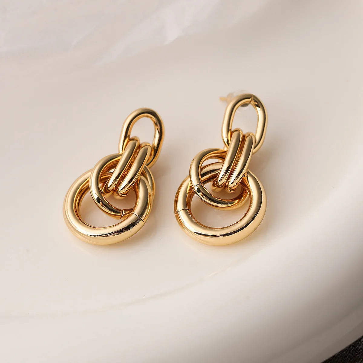 A pair of real gold coloured geometric earrings with an irregular shape, made from copper, style wild.