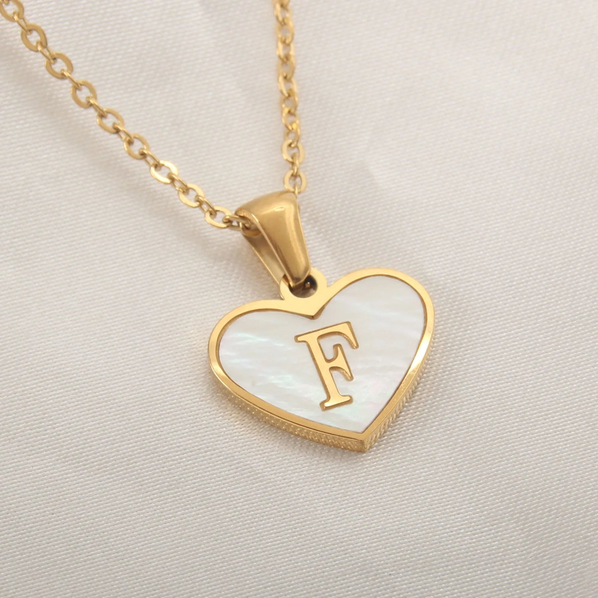 Gold-plated heart necklace with white shell pendant personalised with a letter, on an adjustable chain.