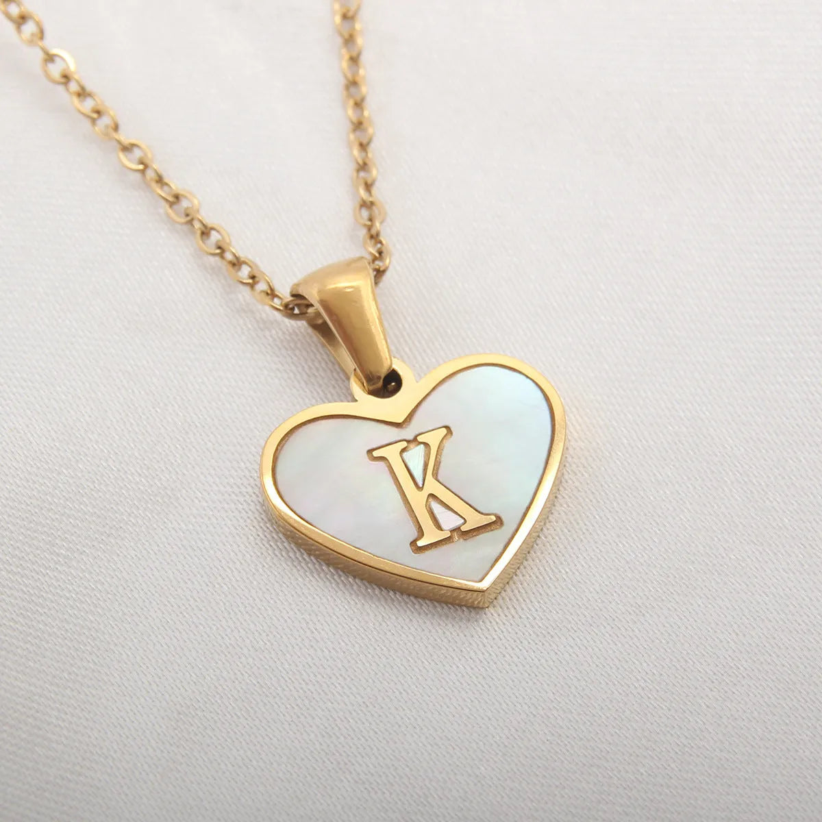 Gold-plated heart necklace with white shell pendant personalised with a letter, on an adjustable chain.