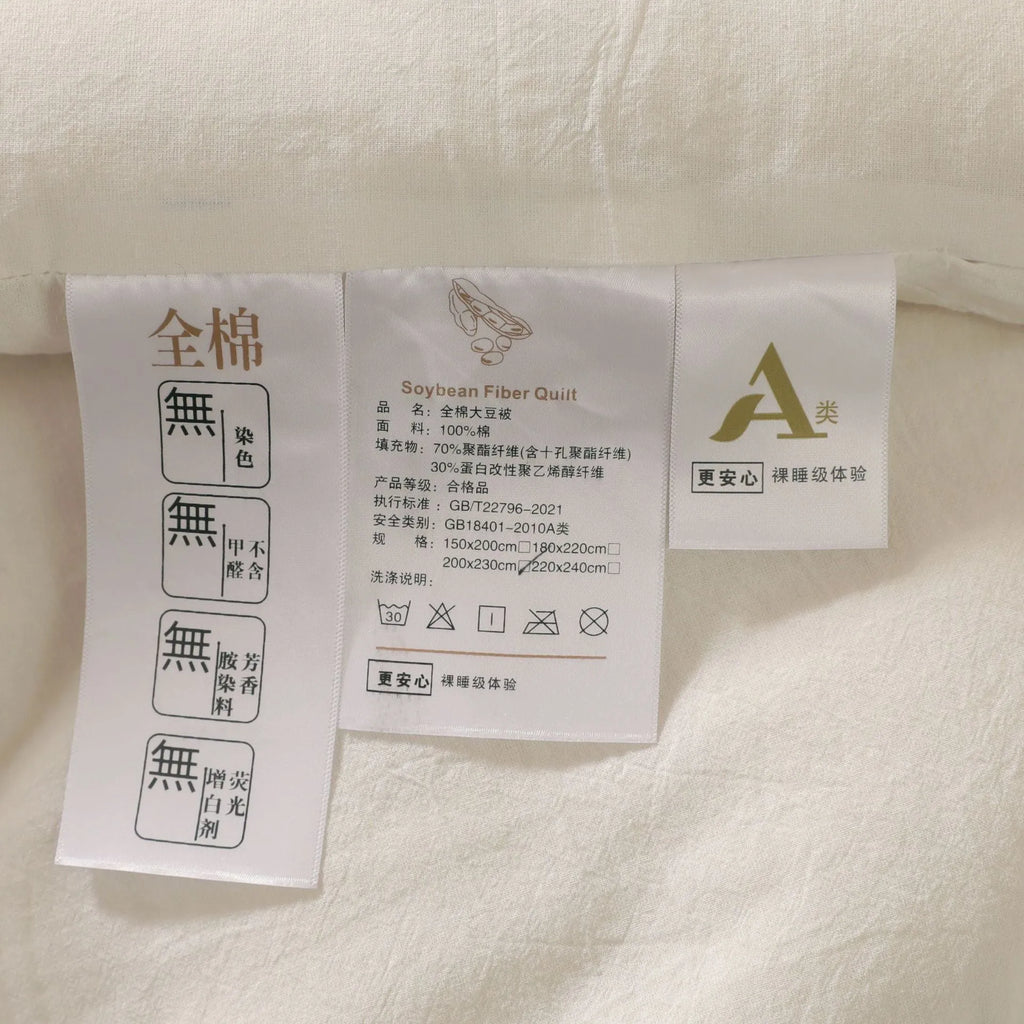 A pure cotton soybean fibre airable quilt in grey, shown with a zipper detail, on a bed.