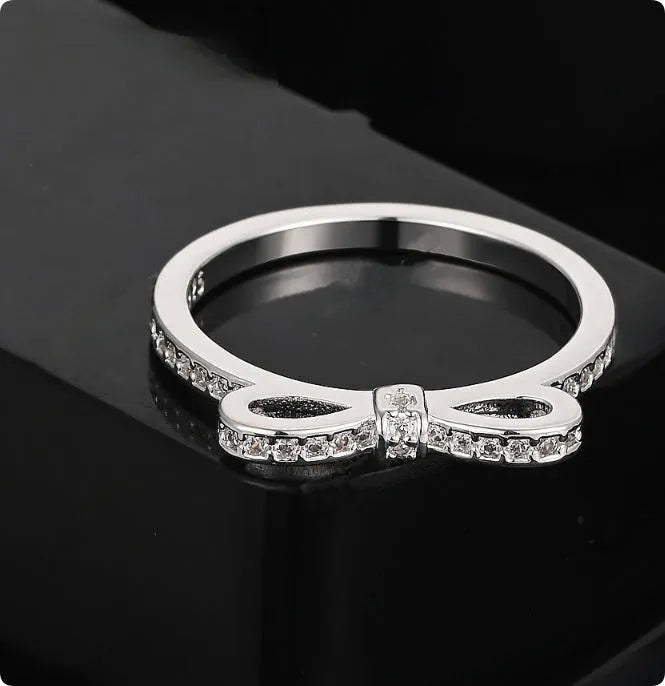 Silver couple style ring with a rhinestone and zircon crystal bow design on a finger.