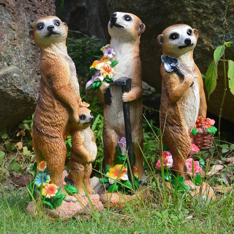 Three small straw hat mongoose garden ornaments: one with a baby, one holding a rake, one holding a shovel.