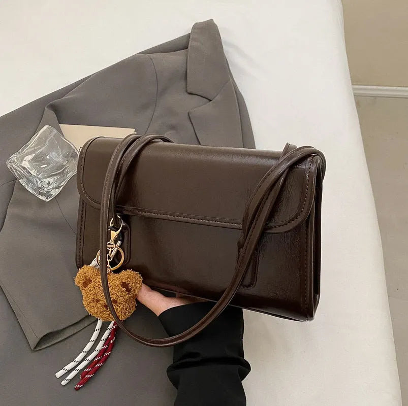 Brown women's structured square PU leather shoulder bag with a detachable tassel pendant and double straps.