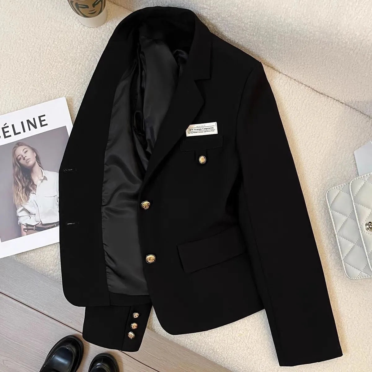 Women's black loose-fit short suit coat with long sleeves and pocket details.