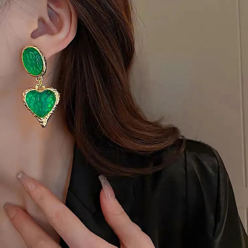 Oval-shaped love heart stud earrings with a pleated silver texture in purple, red, green, and yellow/white colours.