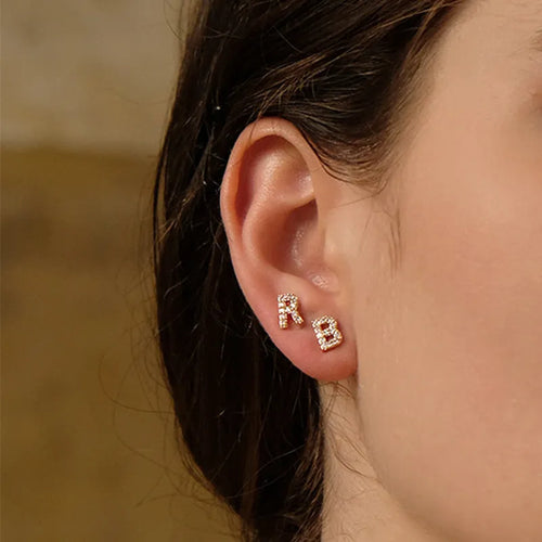 Gold-plated brass alphabet earring showing a single letter with zircon detail on a copper base.