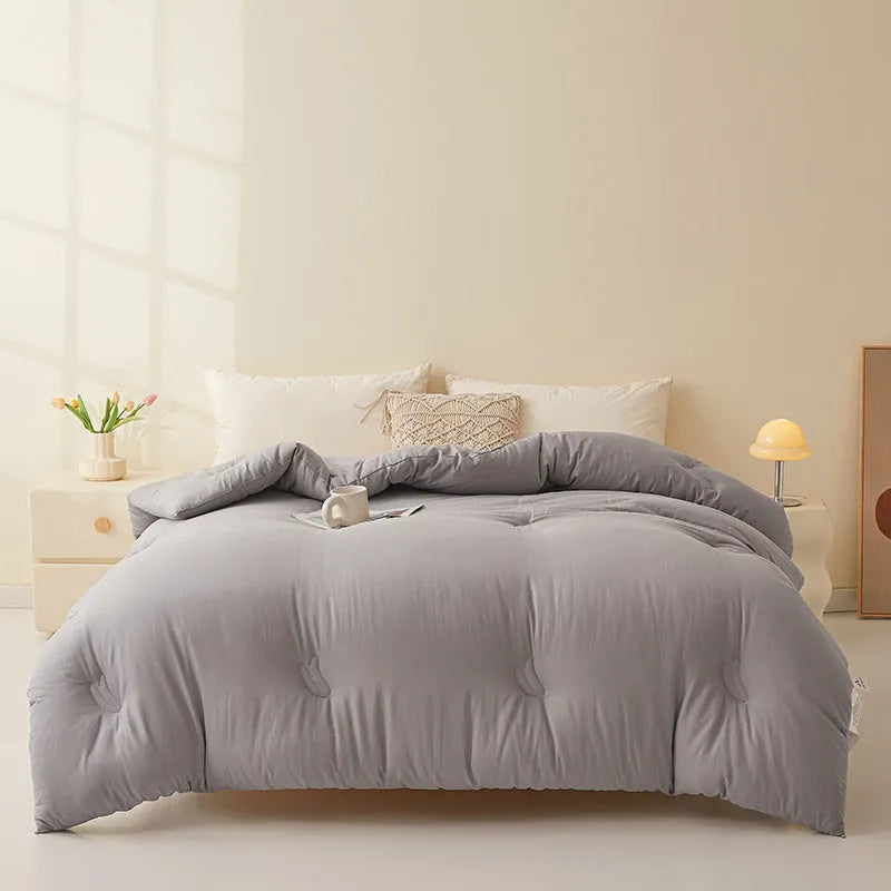 A pure cotton soybean fibre airable quilt in grey, shown with a zipper detail, on a bed.