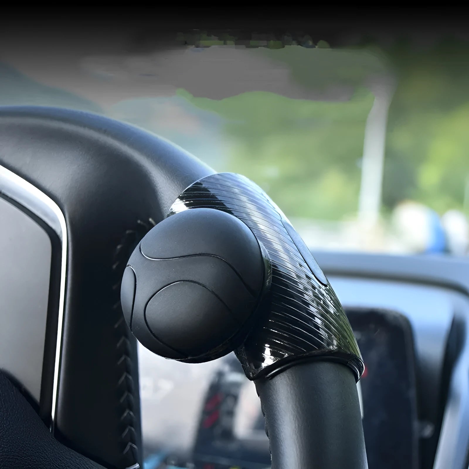 Close-up of black silicone steering wheel assist ball with metal bearing mechanism attached to a car steering wheel rim