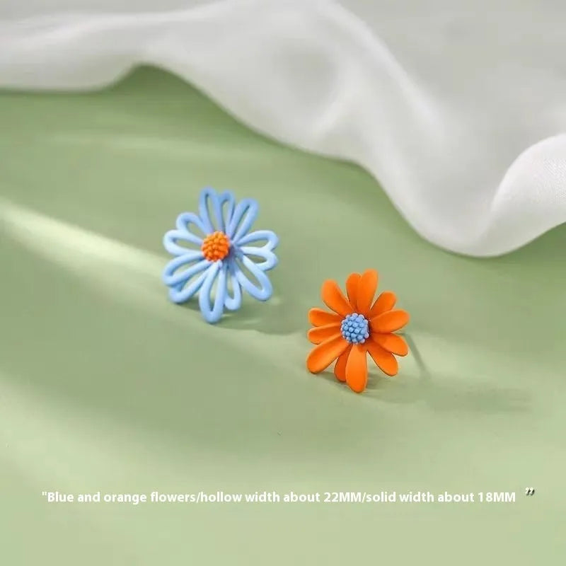 A pair of cartoon-style flower stud earrings in alloy, showing a blue and orange two-tone colour variant.