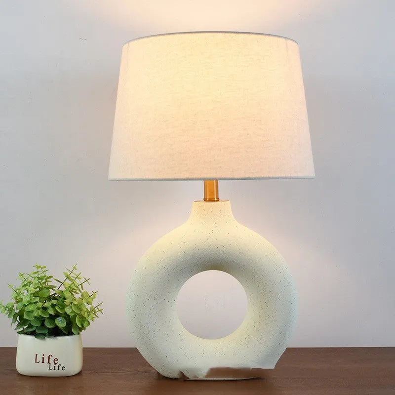 Japanese-style white ceramic table lamp with a button switch on a wooden desk.