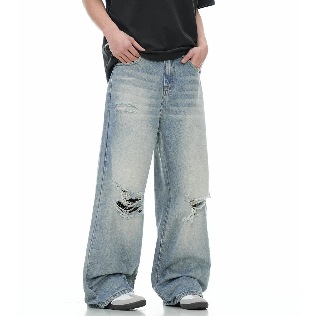 Man wearing blue straight-leg jeans with ripped detailing and an adjustable waistband.