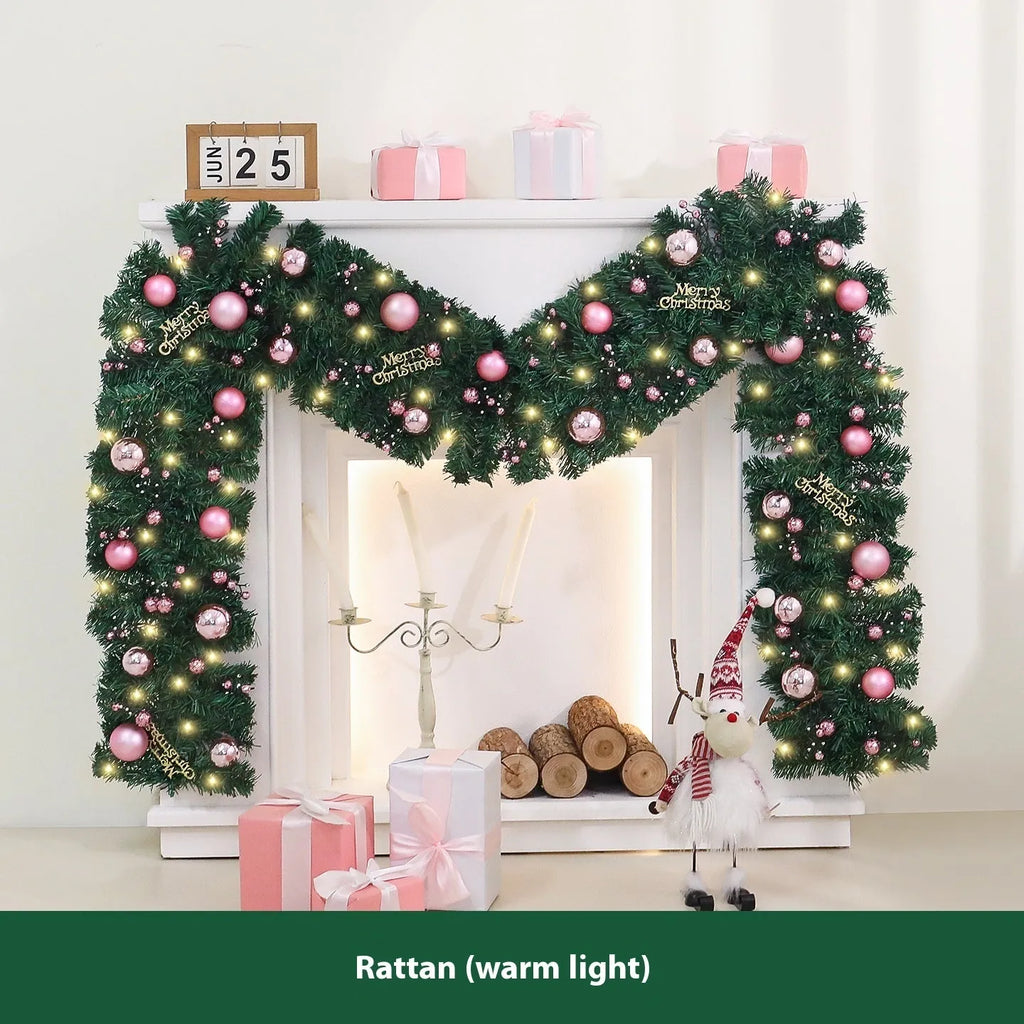 Long pink rattan Christmas garland with small fruit details and optional warm white lights draped on a mantle.