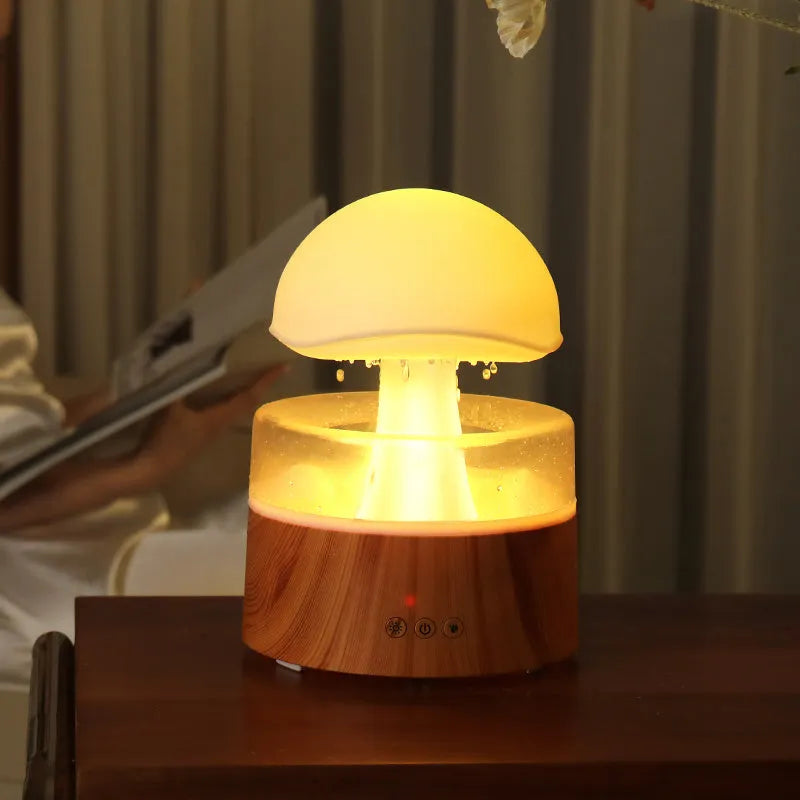 White cloud-shaped humidifier diffuser with LED rain effect and remote control on a wooden table.