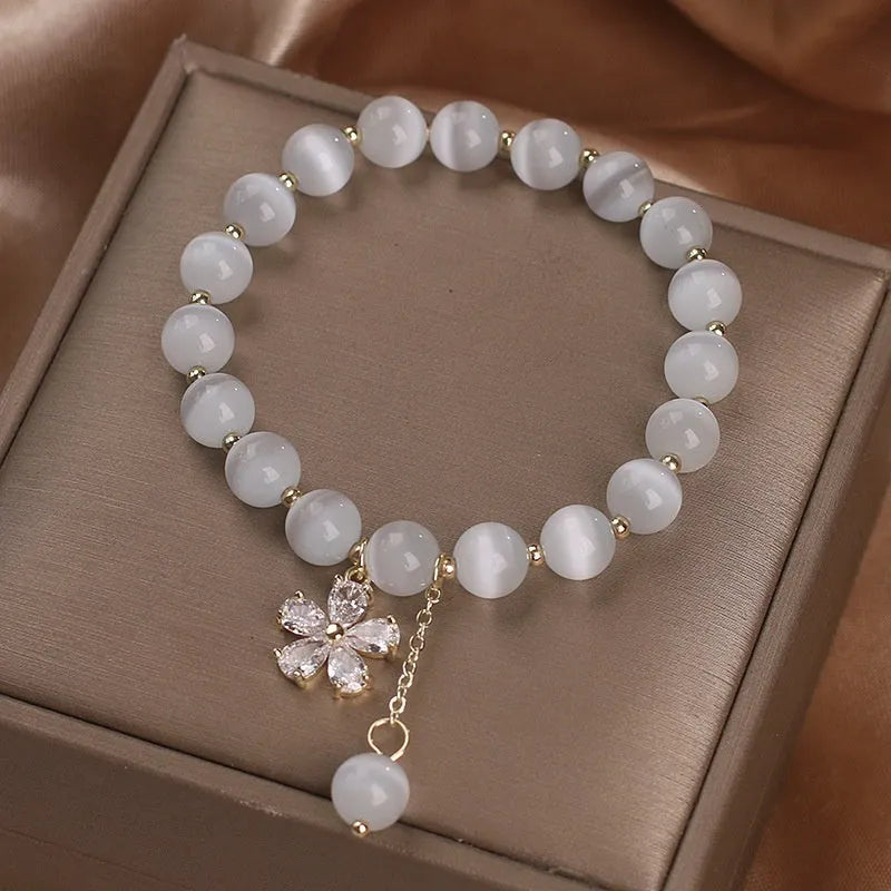 Women's single loop white cat's eye crystal bracelet with flower tassel and morganite safety buckle pendant.