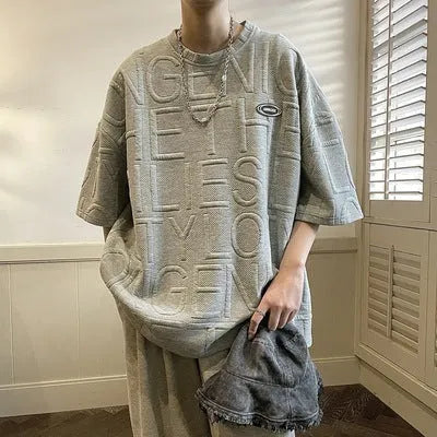 Men's grey short sleeve t-shirt with a raised white 3D letter pattern on the chest