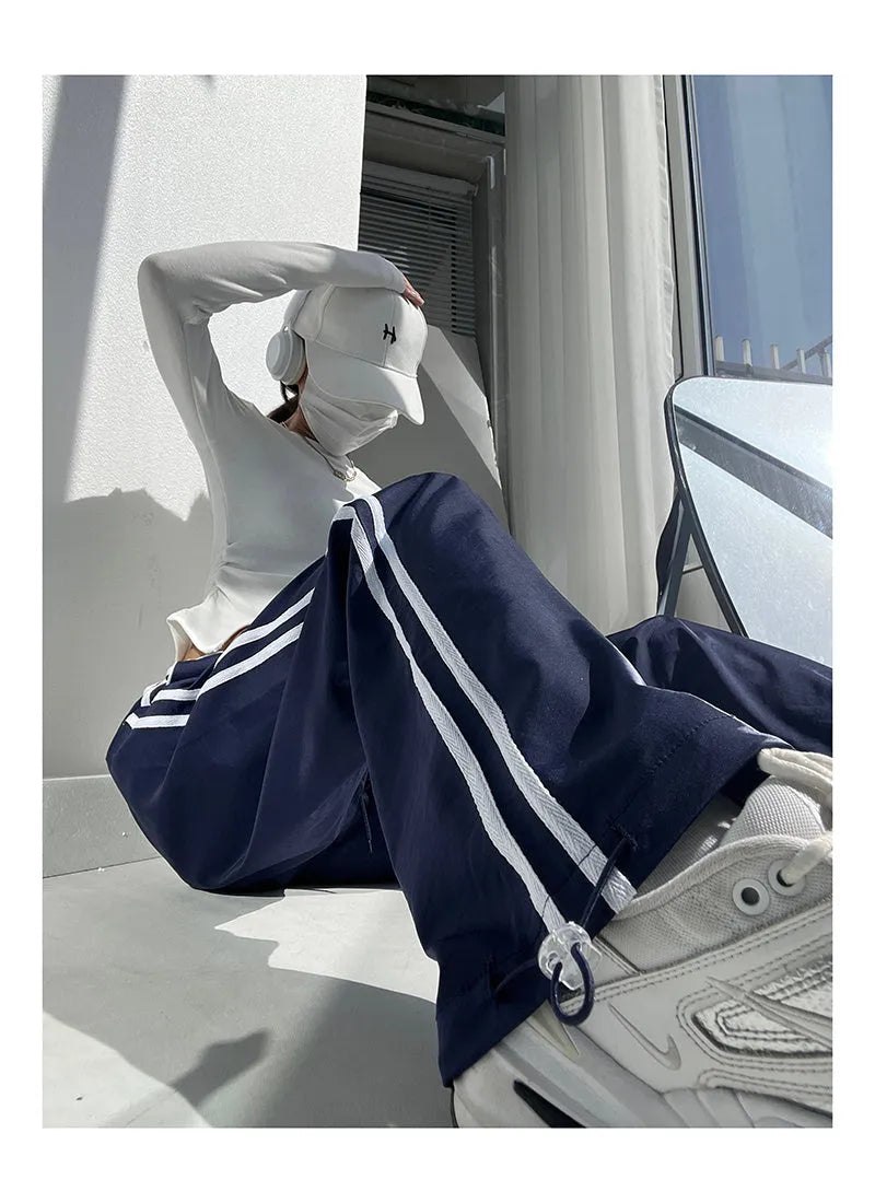 Women's navy blue loose straight leg trousers with ribbon parallel bars detail on the leg.
