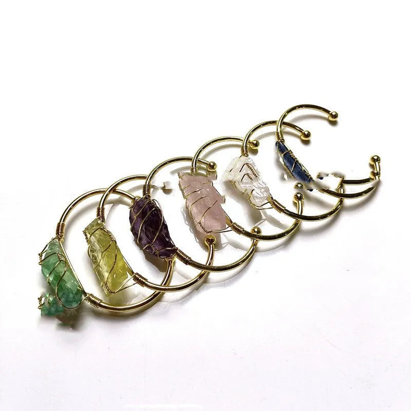 Geometric natural crystal bracelet with gold metal winding on a wrist.