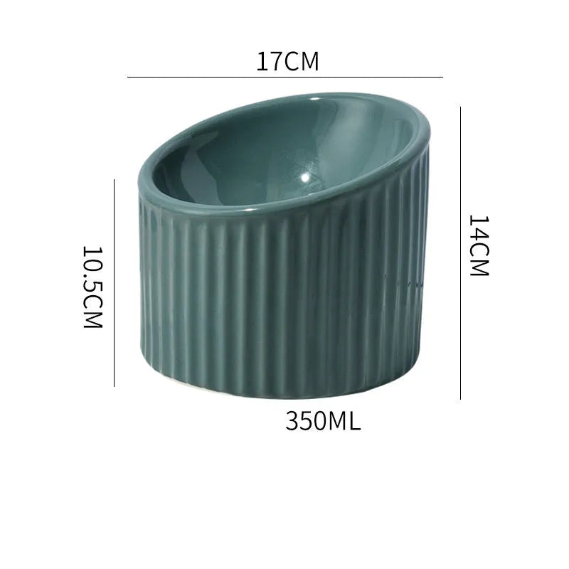 Dark green elevated ceramic cat bowl on a wooden floor, showing its raised height and round, whisker-friendly shape.