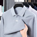 Men's grey loose fit cotton polo shirt with lapel collar and long sleeves on a hanger