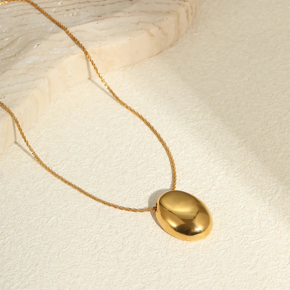 Gold geometric pendant necklace on a model, showing the adjustable chain length.