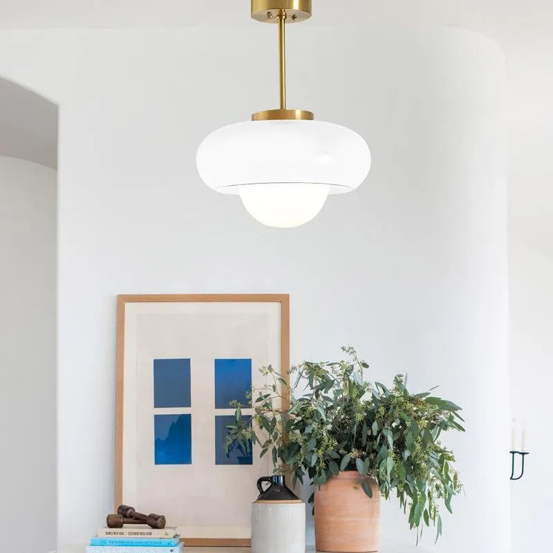 Three-headed Bauhaus pendant light with milky white glass egg tart shades hanging from a ceiling.