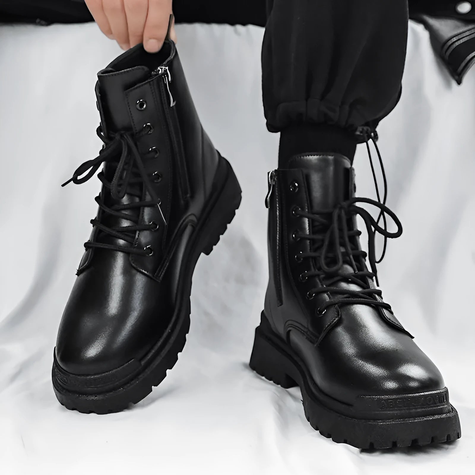 Men's black mid-top British leather boots with flat rubber sole on a neutral background