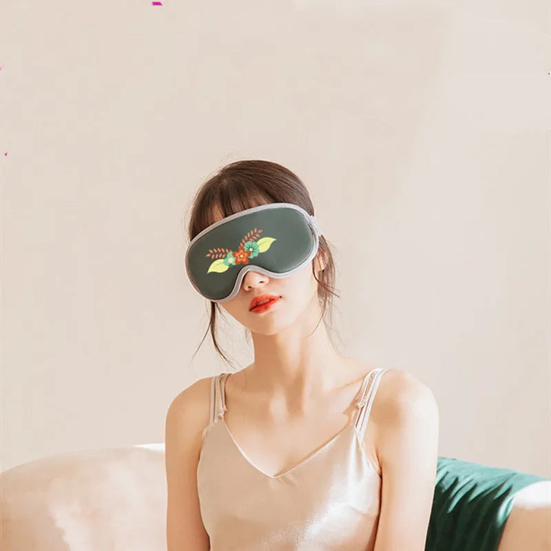 Pink and green portable eye SPA massage goggles showing USB port and suede exterior.
