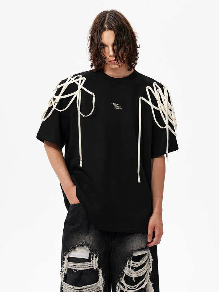 Black loose fit short sleeve T-shirt with ribbon and rivet decorated padded shoulders.