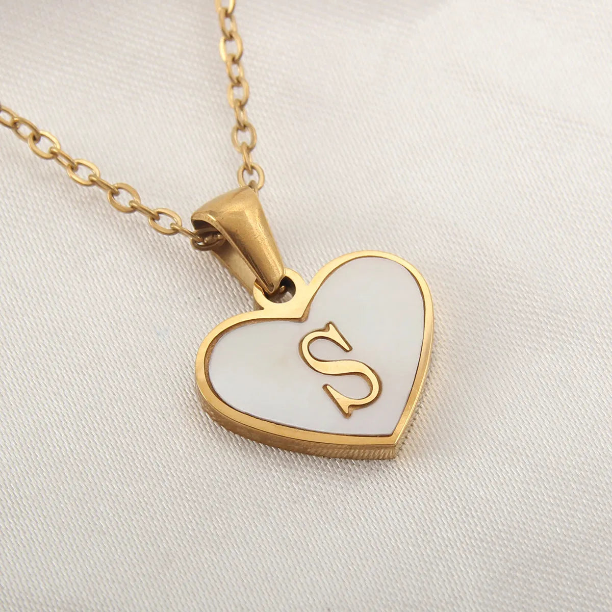 Gold-plated heart necklace with white shell pendant personalised with a letter, on an adjustable chain.