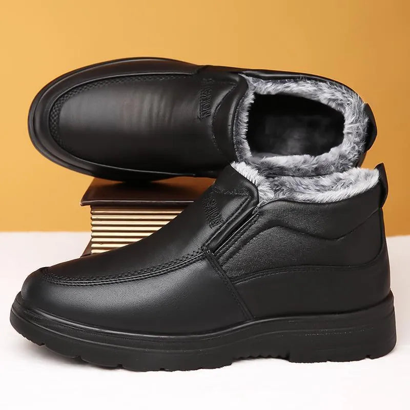 Men's black and brown fleece-lined winter slip-on shoes with rubber soles on a wooden floor.