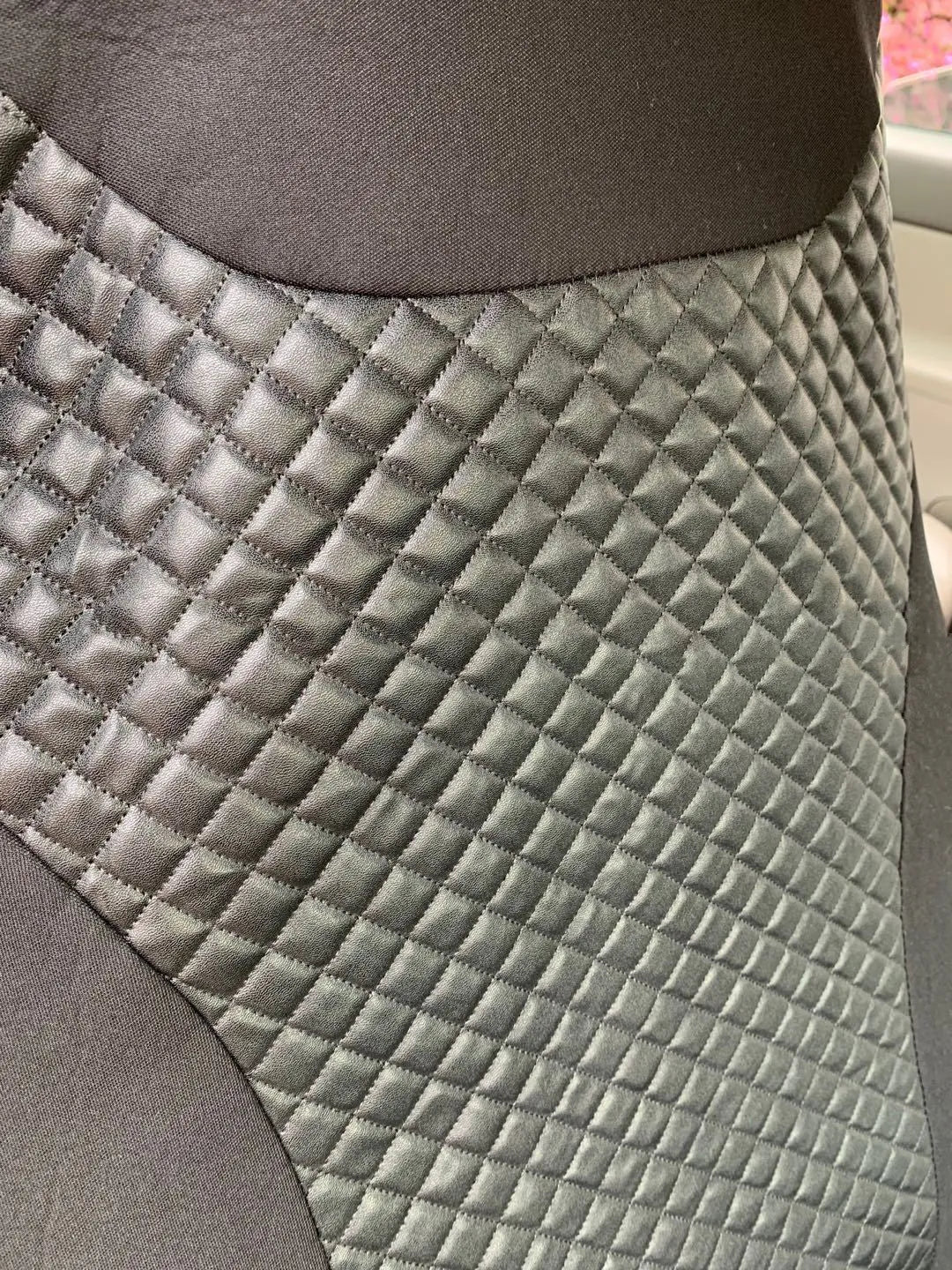 Black quilted automotive seat cover with PU and polyester construction showing plastic hooks