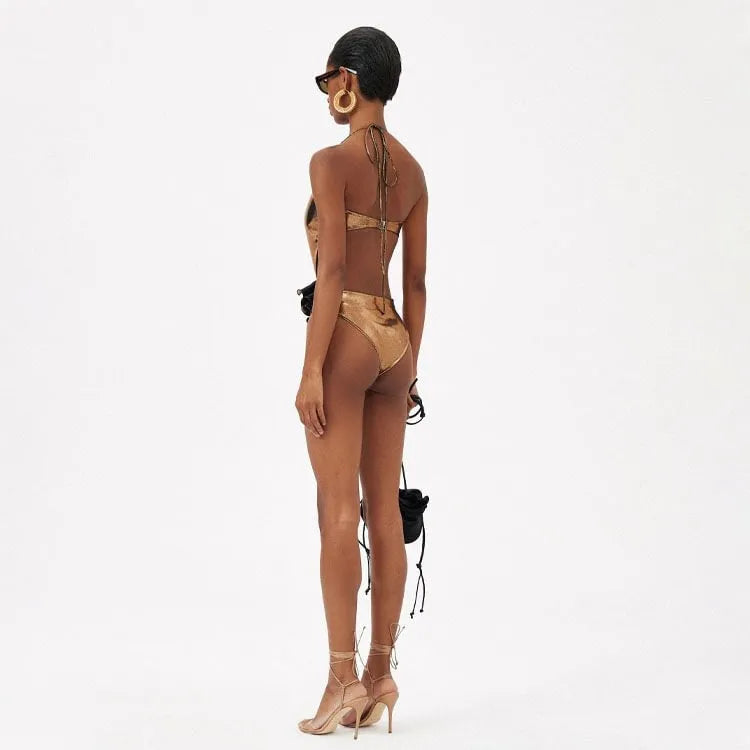 Handmade gold halter neck one-piece swimsuit with hollow out design on a mannequin.