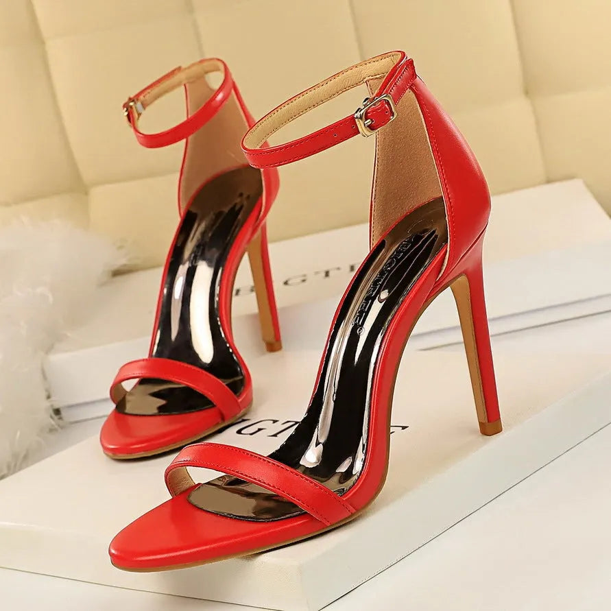 White high-heeled sandal with an open toe and a buckle-fastened ankle strap.