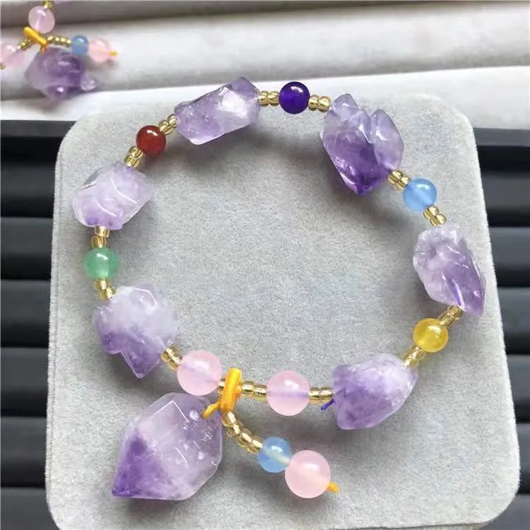 Close-up of a purple natural amethyst bead bracelet with a fu charm for women, on a white background.