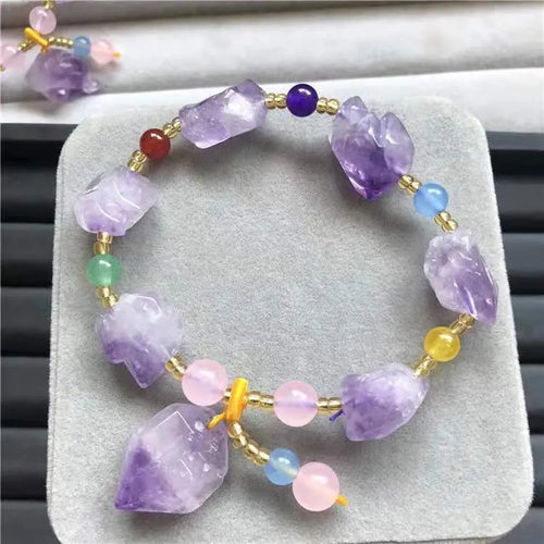 Close-up of a purple natural amethyst bead bracelet with a fu charm for women, on a white background.
