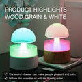 White cloud-shaped humidifier diffuser with LED rain effect and remote control on a wooden table.