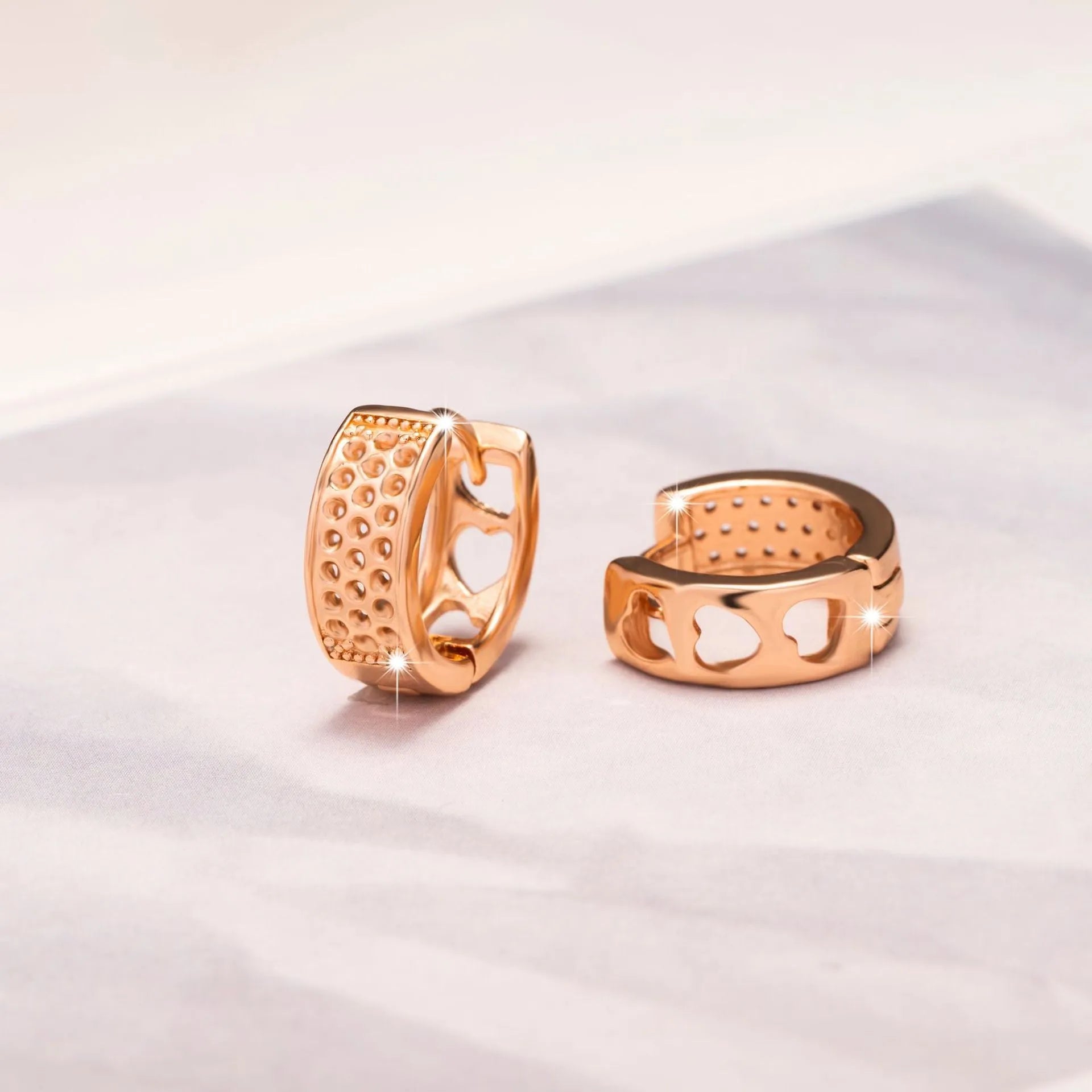 Rose gold women's earrings with three hollowed heart shapes in circular design