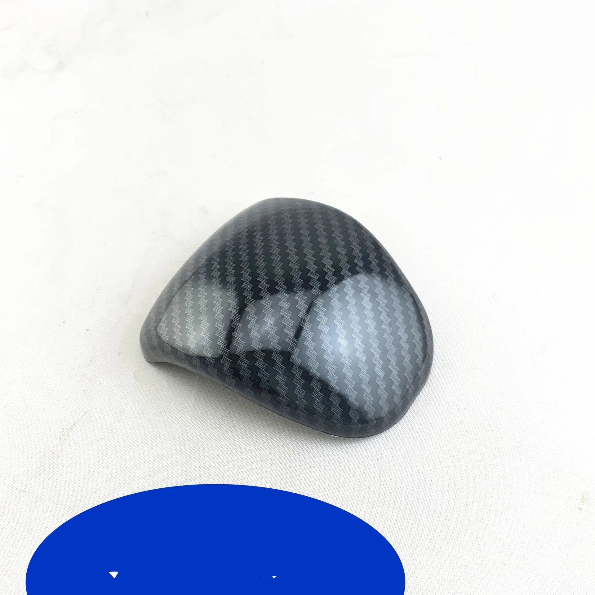 Black gear shift cover with a carbon fibre pattern for car interior styling.
