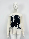 Grey women's alpaca wool pullover sweater with abstract pattern and tassel detailing on a hanger.