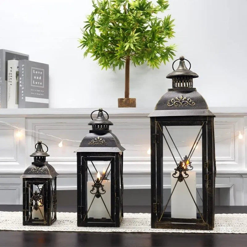 Black wrought iron floor-standing storm lantern with tempered glass panels for outdoor candle lighting