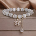 Women's single loop white cat's eye crystal bracelet with flower tassel and morganite safety buckle pendant.