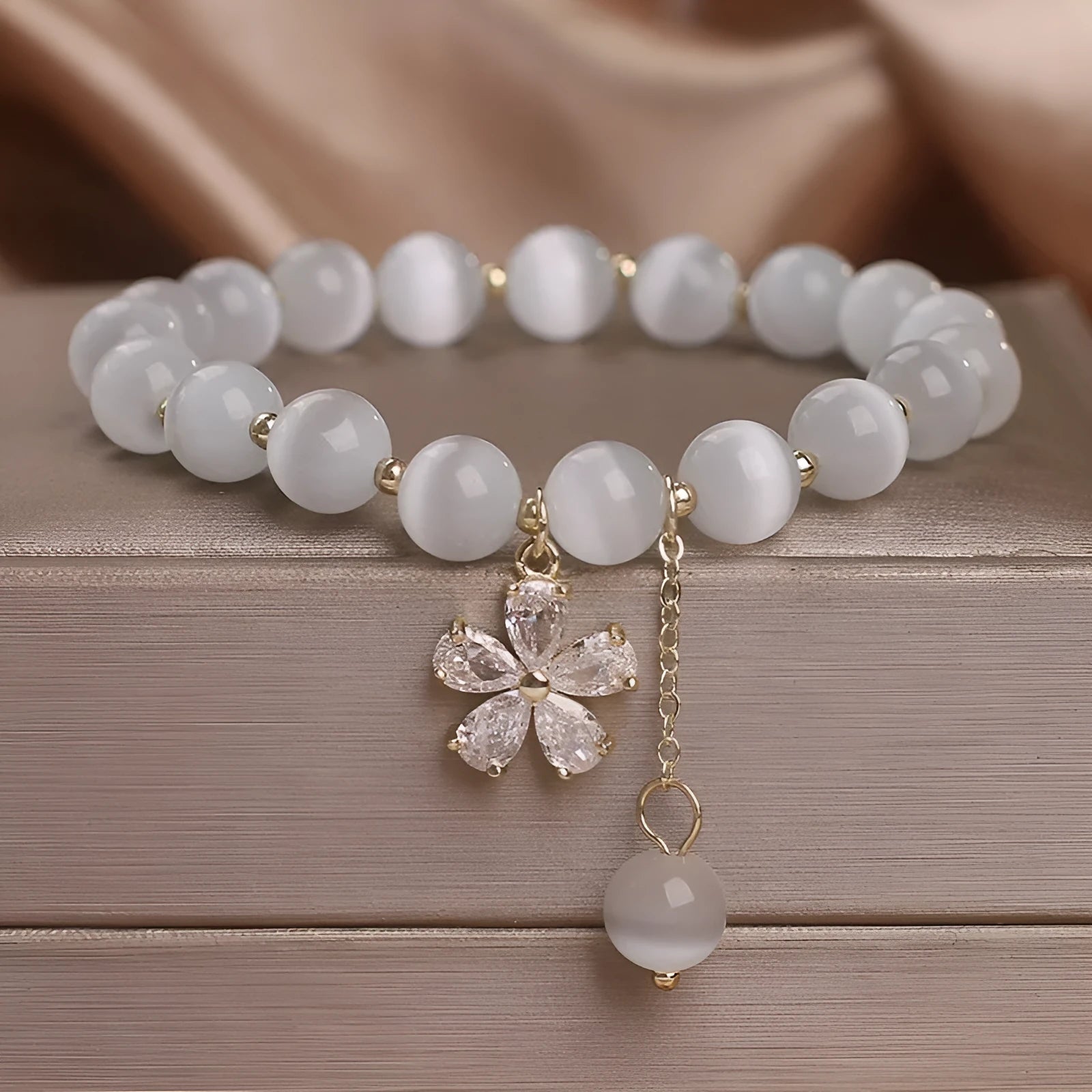 Women's single loop white cat's eye crystal bracelet with flower tassel and morganite safety buckle pendant.
