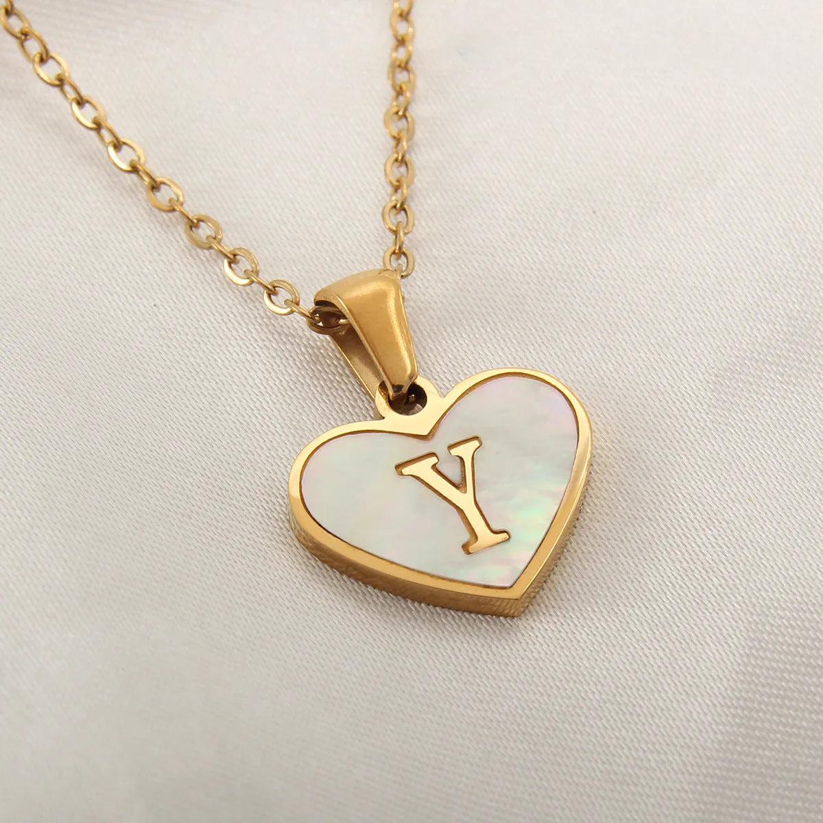 Gold-plated heart necklace with white shell pendant personalised with a letter, on an adjustable chain.