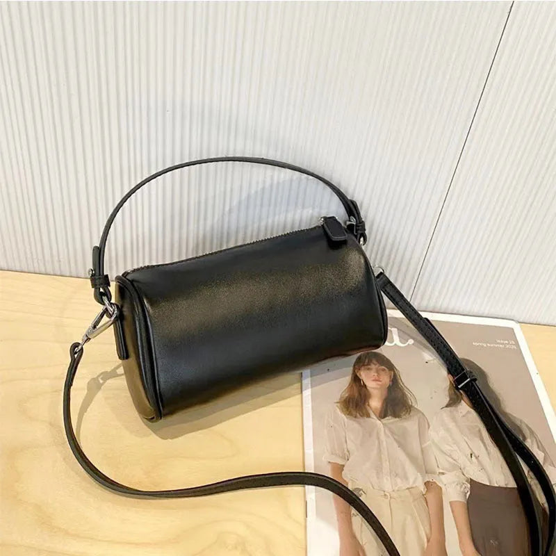 Soft genuine leather cylindrical crossbody bag for mobile phones, shown in a street style with visible stitching.