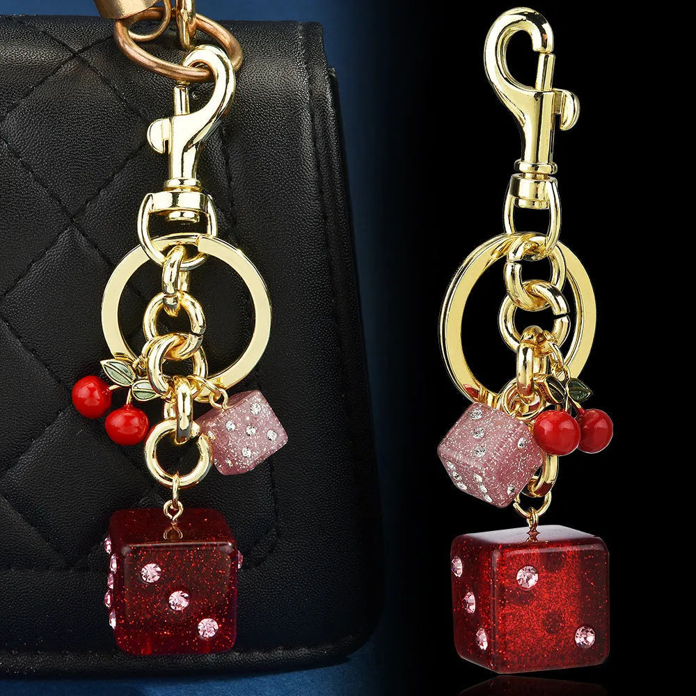 Square metal keychain pendant with a vintage two-tone cherry dice pattern on a white background.