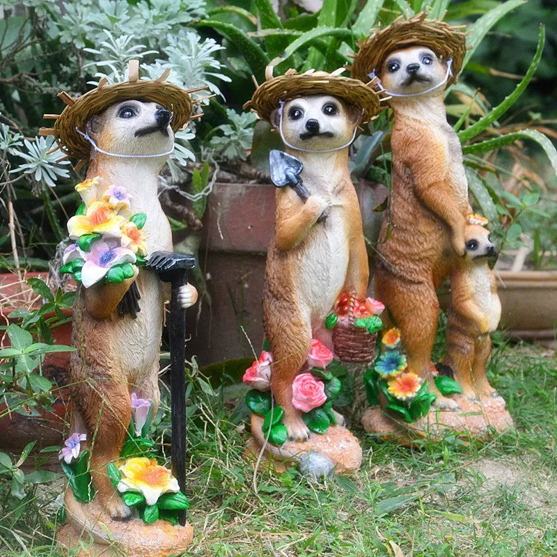 Three small straw hat mongoose garden ornaments: one with a baby, one holding a rake, one holding a shovel.