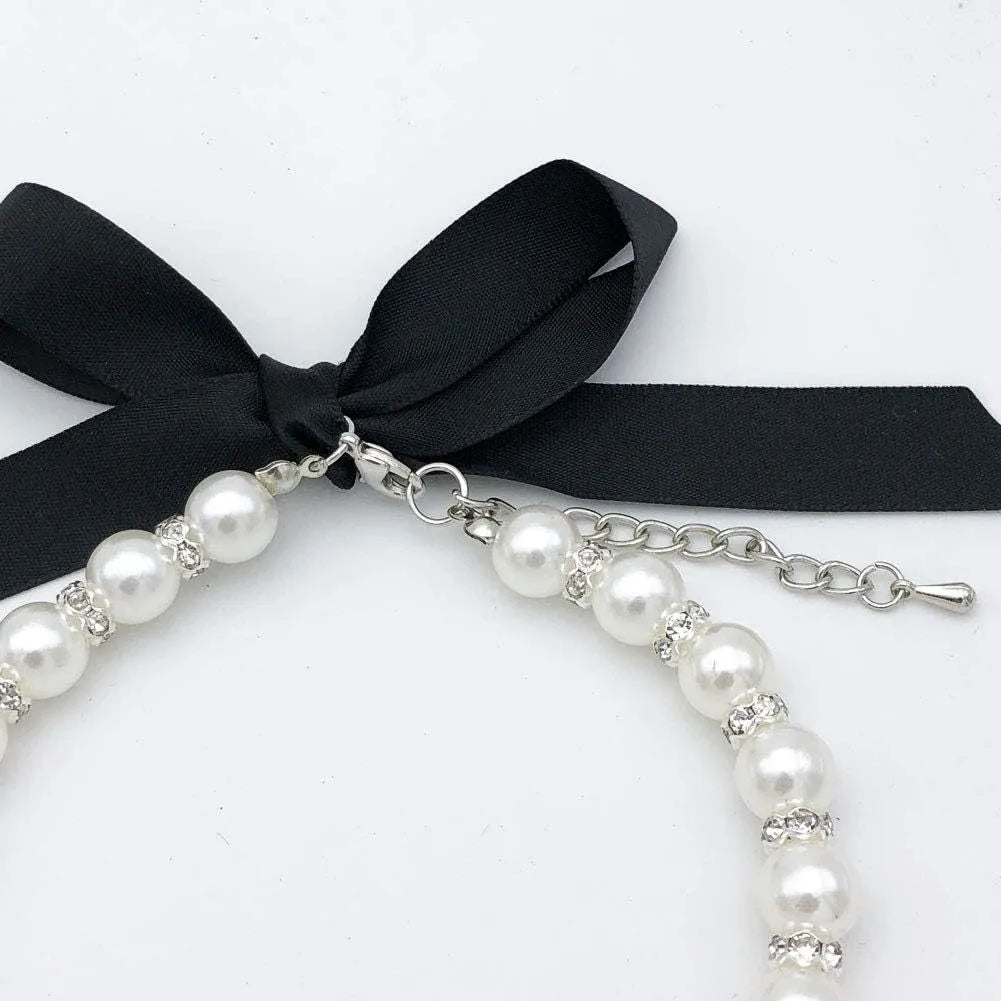 Adjustable diamond dog pearl necklace with rhinestones and ribbon bow in blue, pink, purple, or white.